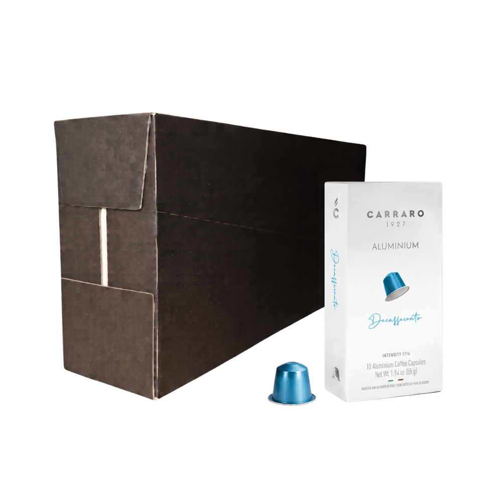 Carraro 1927 decaffeinated aluminium coffee capsules shown with a large dark brown cardboard box, a white sachet package, and one blue aluminium capsule on a clean white background.