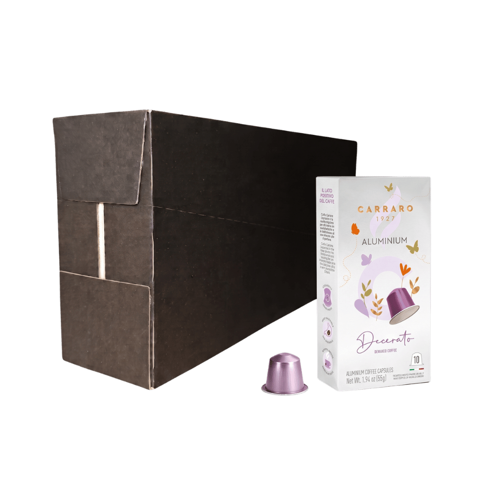 Carraro Decerato aluminum coffee capsules shown with a large dark brown cardboard shipping box, a white branded product box, and one individual metallic purple capsule on a plain white background.